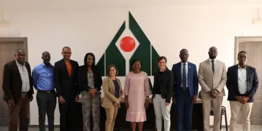 Group of diverse people posing for photo in front of CESAG logo on wall.