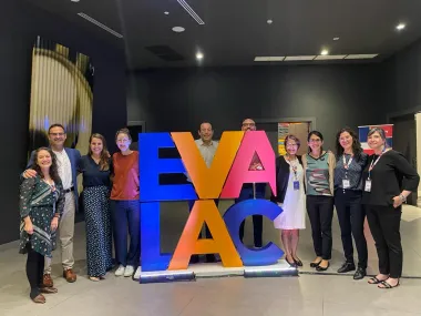 Group stands around EVALAC logo sculpture for photo.